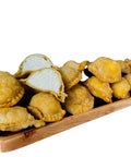 Mehrere Pastelitos mit Käse auf einem Holztablett und erkennbarer Füllung